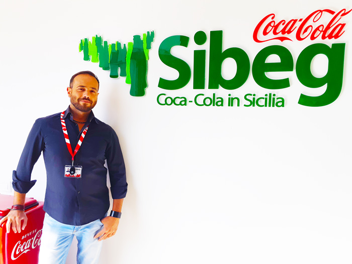 G. Russo standing next to the Sibeg and Cocacola sign