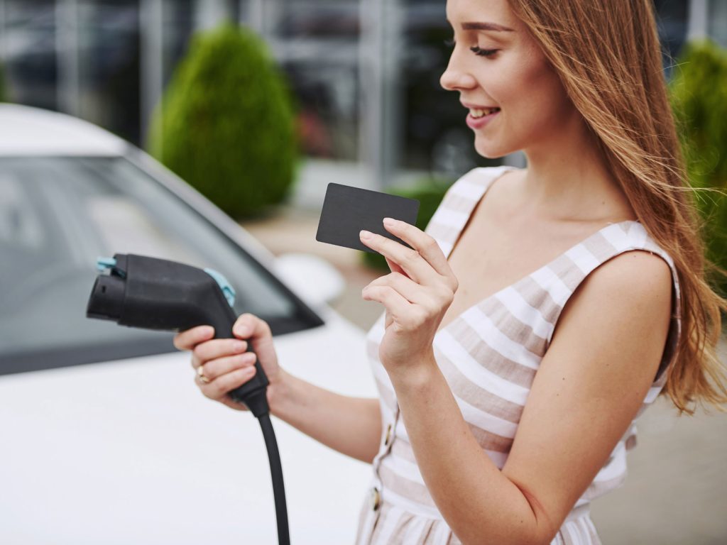Giovane donna con card personalizzata per la ricarica dell'auto elettrica