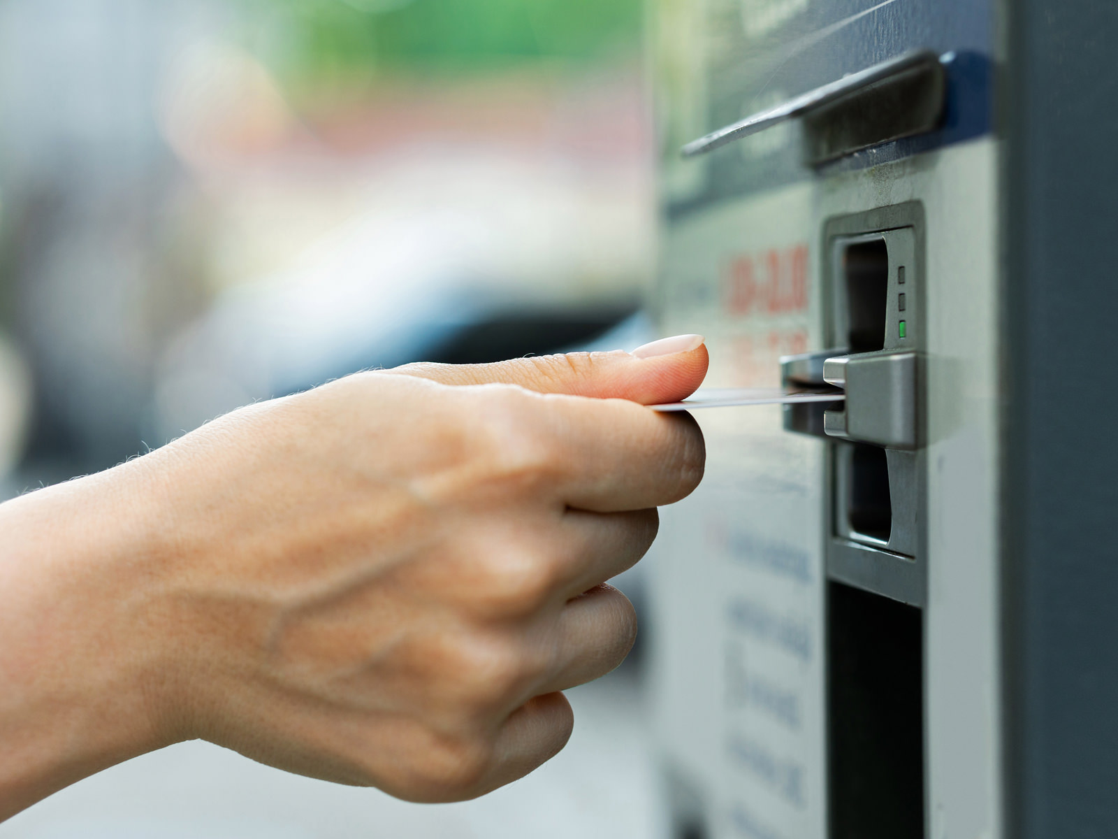 Closeup of female hand with a credit card and ticket vending machine